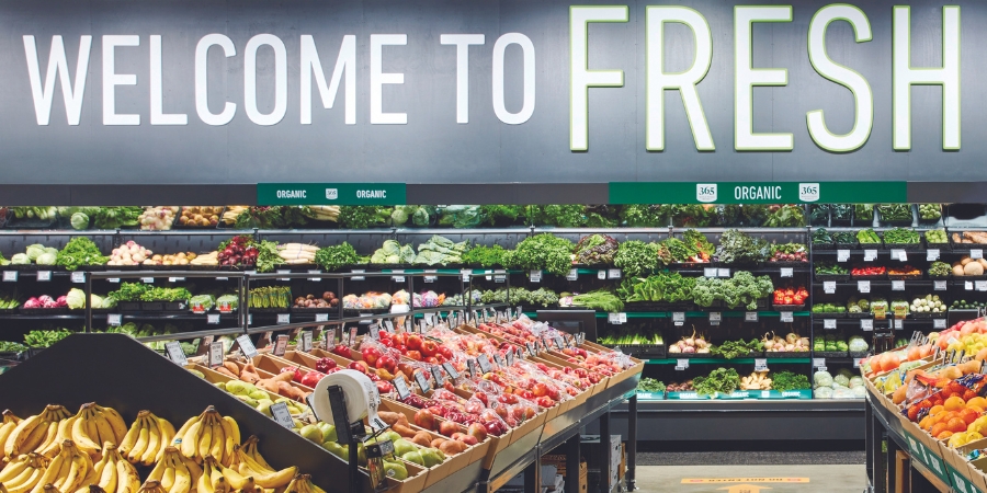 Inside of an Amazon Fresh store with the sign "Welcome to Fresh" above fruits and veggies