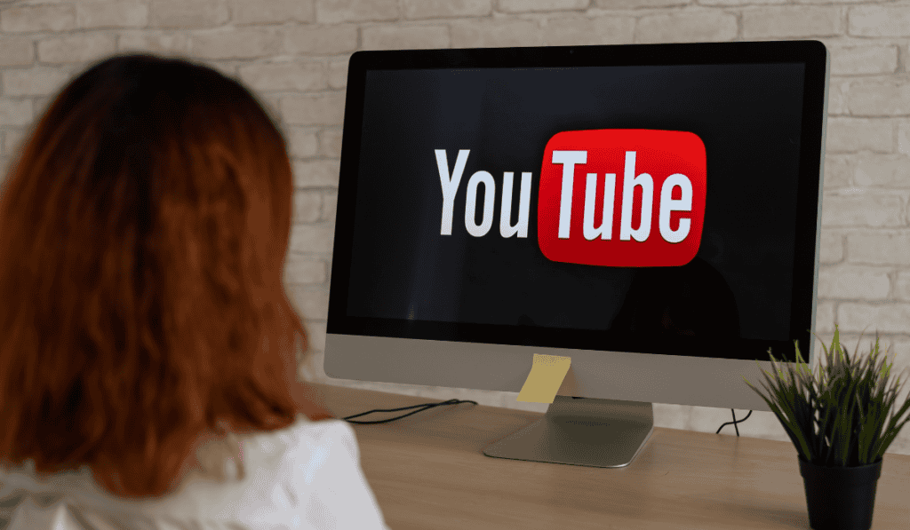 Woman looking at a computer screen with the YouTube logo on it